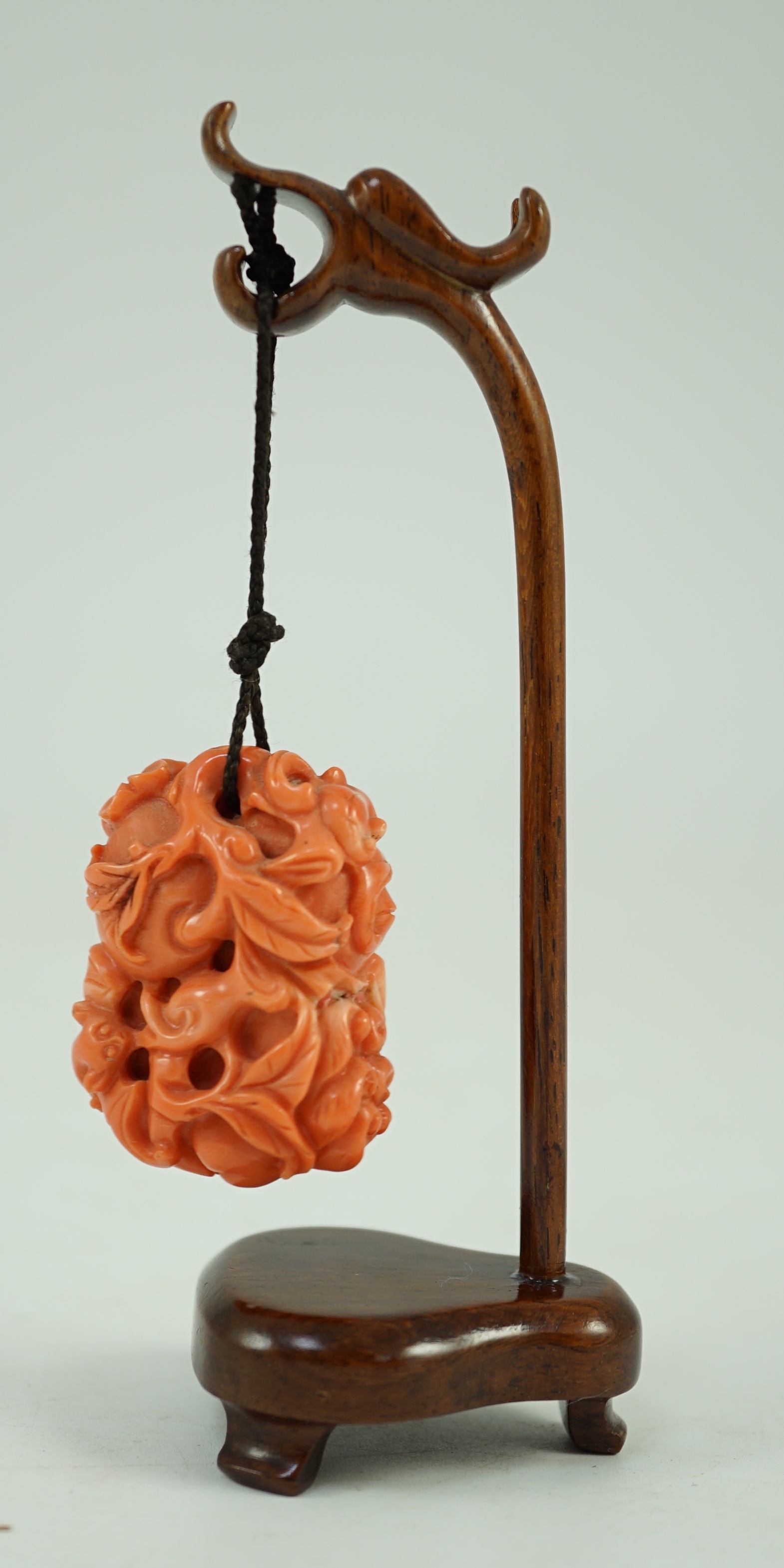 A good Chinese coral ‘fruit and bats’ pendant, 19th century, 3.7cm, later suspension stand